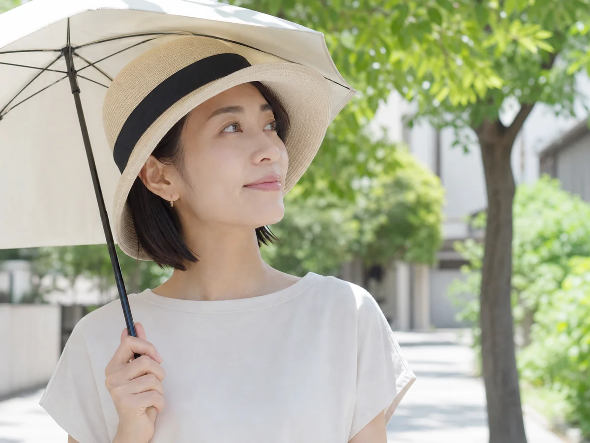 日傘と帽子で日差しを避ける女性
