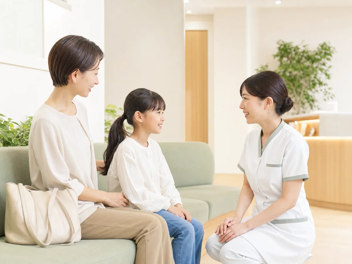 親子に受診の案内をする看護師